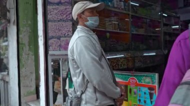 Corona virüsü vakalarında yüz maskesi takan bir adam gerekli malzemeleri topluyor.
