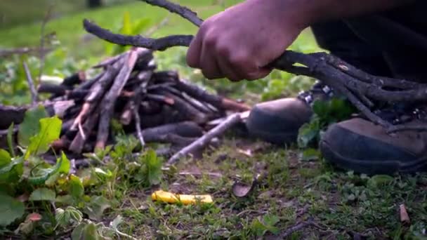 Man zit op de grond Breaking Tree Takken met behulp van zijn voeten op daglicht — Stockvideo