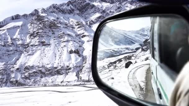 Kış boyunca engebeli dağ arazisinde sürülen bir arabanın dikiz aynası perspektifi — Stok video