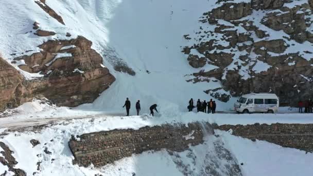 Вид с воздуха на группу путешественников, убирающих блокпост, убирая снег с опасных дорог Спити — стоковое видео