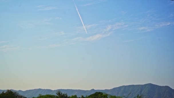 Piękne ujęcie samolotu pozostawiającego za sobą smugi na błękitnym niebie z górami — Wideo stockowe