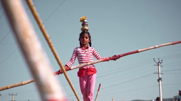 Interessante video van meisje het uitvoeren van een touw lopen op een tier terwijl het houden van gewicht op haar hoofd en handen in pushkar kameel eerlijk — Stockvideo