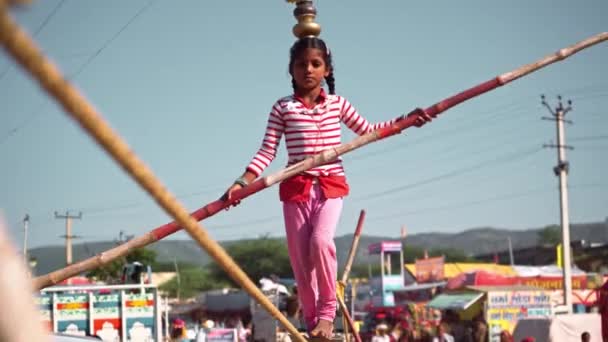 Vídeo interessante de menina realizando uma caminhada de corda em um nível enquanto segurando peso em sua cabeça e mãos em pushkar camelo justo — Vídeo de Stock