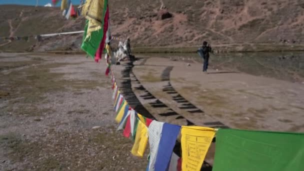 Pohybující se záběr muže zarámovaný modlitebními vlajkami cvakající obrázky na jezeře Chandratal, Spiti Valley — Stock video