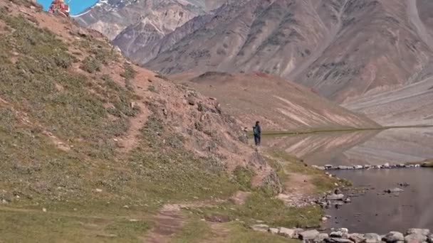 Voorwaarts bewegend schot van een man die loopt naar een transparant meer bij chadratal, spiti — Stockvideo