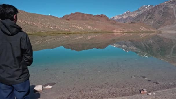 Aufschlussreiche filmische Aufnahme eines Mannes, der am Ufer des gewaltigen Himalaya-Sees in Chandratal, Spiti-Tal, steht, breite Rückseite — Stockvideo