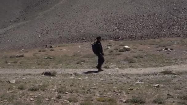 Sideways volgen schot van een man trekking naar beneden in de berg — Stockvideo