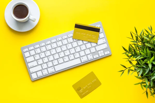 shopping online payment. Card on keyboard on yellow desk top-down