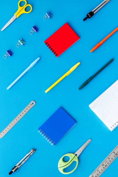School supplies pattern - notebook, pen, ruler, sciccors - on blue table top-down
