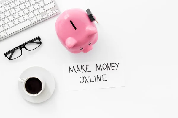 Earn money online. Concept with piggy bank on white desktop. Top view copy space