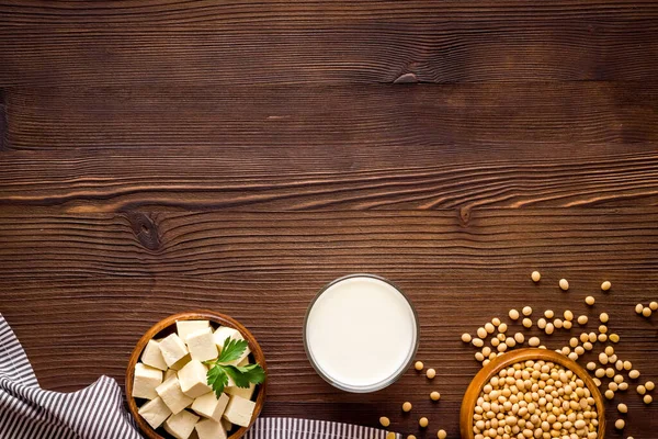 vegan soy milk with soy beans on wooden background top-down copy space