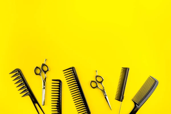Combs, hairbrush, scissors - hairdresser eqiupment - on yellow table top-down space for text