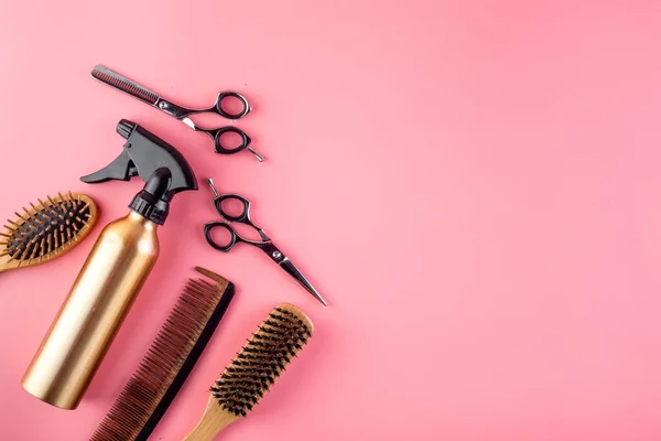 Hairdressing instruments. Combs, scissors and spray on pink desk from above frame space for text