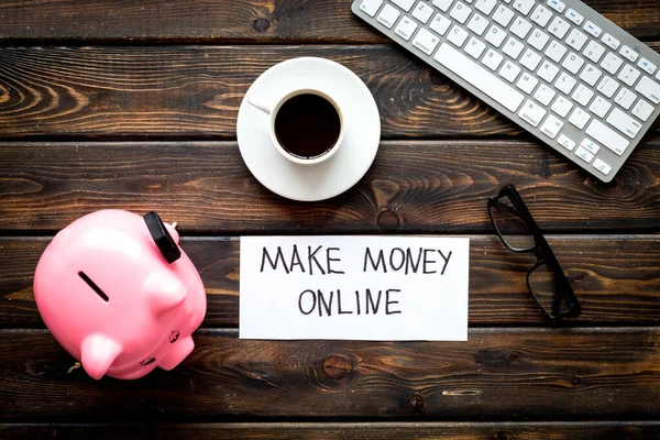 Earn money online. Concept with piggy bank on wooden desktop. Top view