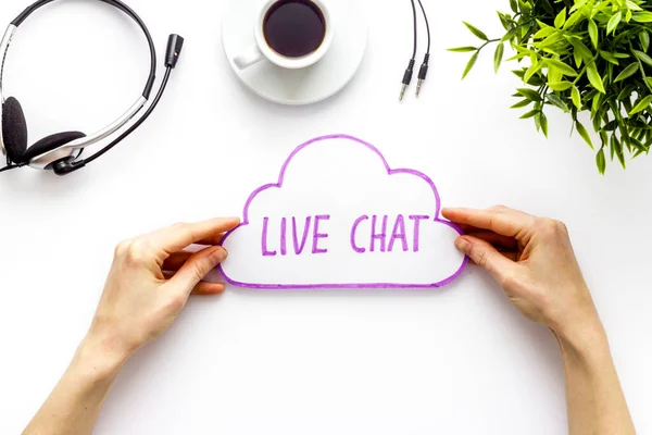 Live chat concept - bubble in hands on white desk top view
