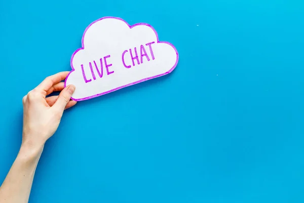 Live chat concept - bubble in hands on blue table top view