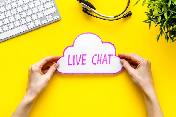 Live chat concept - bubble in hands on yellow table top view