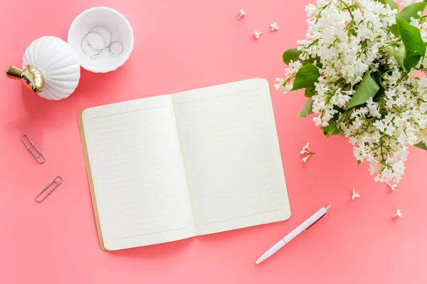 Top view of jasmine flowers bouquet with notebook and cup tea on working place