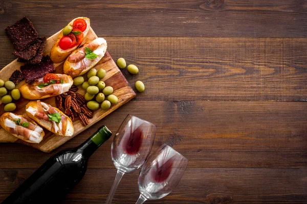 Wine appetizer. Toasts, nuts, olives on wooden desk top view copy space