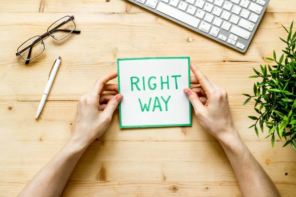 Business desicion. Right way icon in hand on wooden desk top view