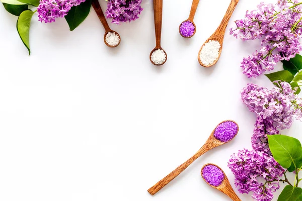 Frame of sea bath salt and purple flowers, top view