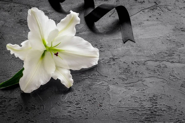 Lily funeral flower on dark stone. Condolence card with copy space