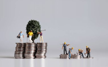 Minyatür insanlar ve bozuk para yığını. Zenginlerin ve fakirlerin hayatları hakkındaki kavramlar.