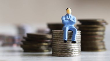 Minyatür insanlar ve para kavramı. Paranın üzerinde oturan adamın minyatürü..