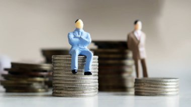 Minyatür insanlar ve para kavramı. Paranın üzerinde oturan adam ve para yığınının arkasında duran adam..
