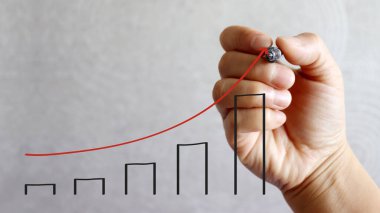 Bir kalem el kırmızı ok ve siyah çubuk grafiği çiziyor.