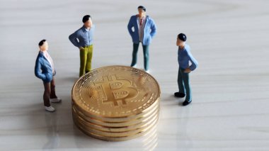 Bitcoin yığınıyla çevrili dört minyatür adam..