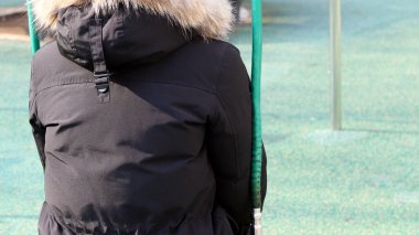 Salıncakta sallanan bir kızın arkasından görünüş.