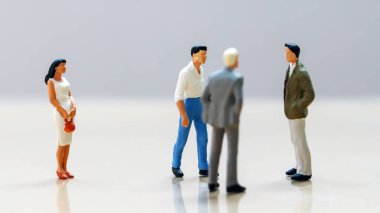 Erkekler ve kadınlar iş başında. Minyatür bir kadın, bir grup minyatür adamın diğer tarafında duruyor..