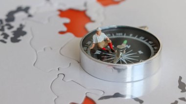 Pusula üzerinde oturan minyatür bir gezgin..