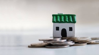 Bozuk paralar ve yeşil çatılı minyatür bir ev..