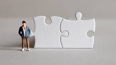Two puzzles and a miniature man standing up. clipart