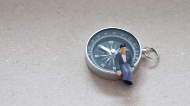 Pusula üzerinde oturan minyatür bir adam..