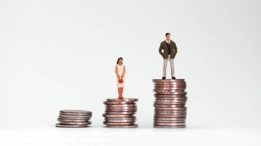Farklı yüksekliklerdeki bozuk paraların üzerinde duran minyatür bir adam ve kadın..