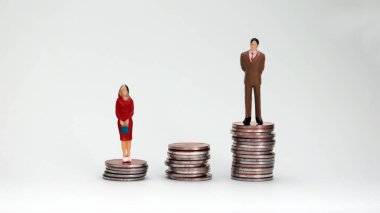 Cinsiyet Ödeme Boşluğu konsepti. Düşük bozuk para yığınının üzerinde duran minyatür bir kadın ve uzun sikkelerin üzerinde duran minyatür bir adam..