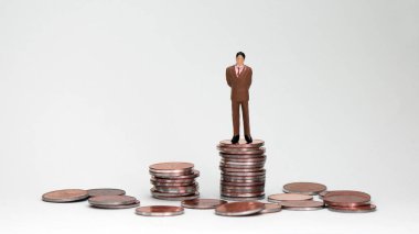 Bozuk para yığınının üstünde duran minyatür bir adam. Başarılı bir erkek kavramı.