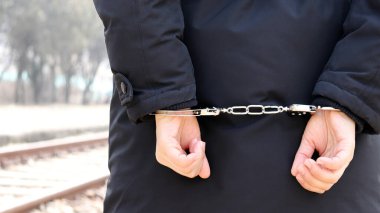 Bir şüpheliyi tutuklayıp kelepçeleyin. Suçlunun arkasından görünüş.