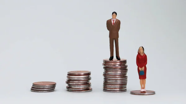 Gender Pay Gap concept. A miniature men and a women are standing on the coin tower.