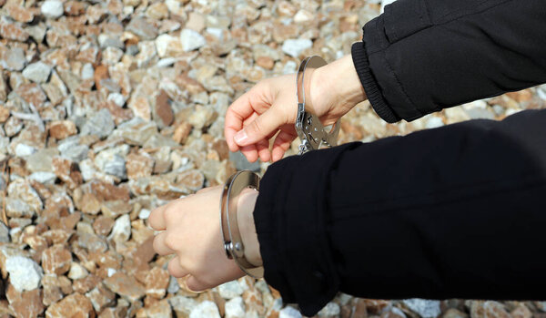 Both hands of a woman in handcuffs.