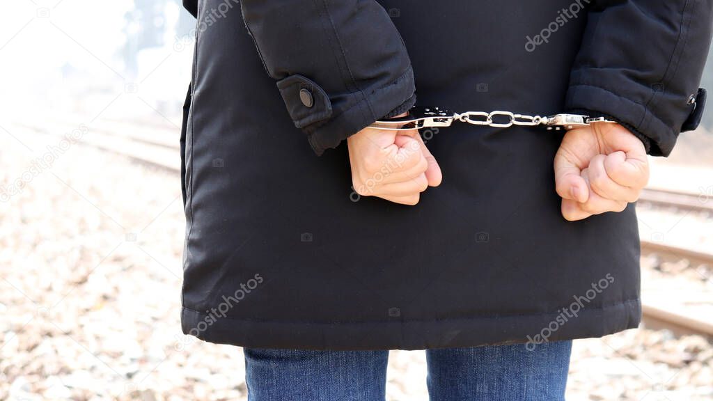 The back of a criminal in handcuffs.