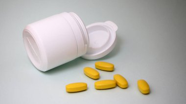 Sarı hapların üzerinde oturan minyatür bir adam..