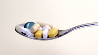 Gümüş kaşıktaki hapların ve kapsüllerin yakın plan görüntüsü..