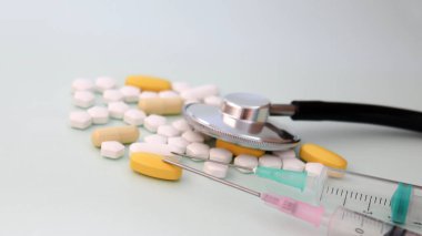 Bir stetoskop ve hapın üstüne konmuş iki tane tek kullanımlık şırınga..