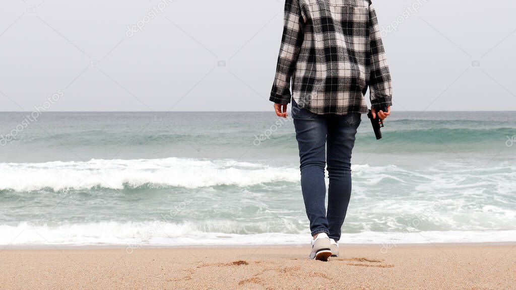 The back of a woman standing on the beach with a gun.