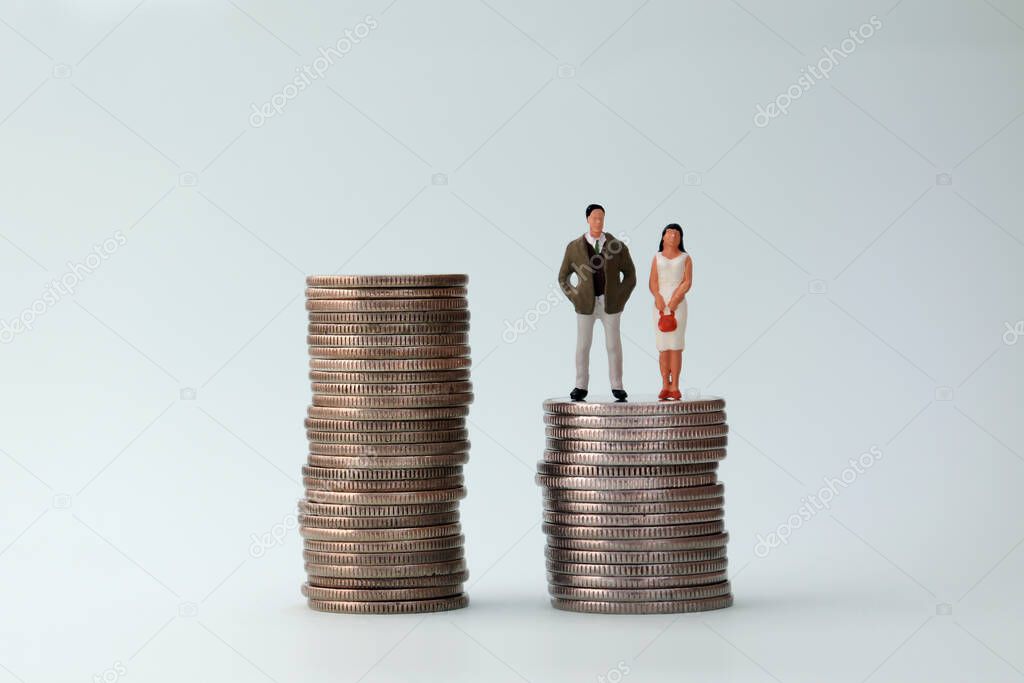 Two piles of coins with a miniature woman and miniature man.