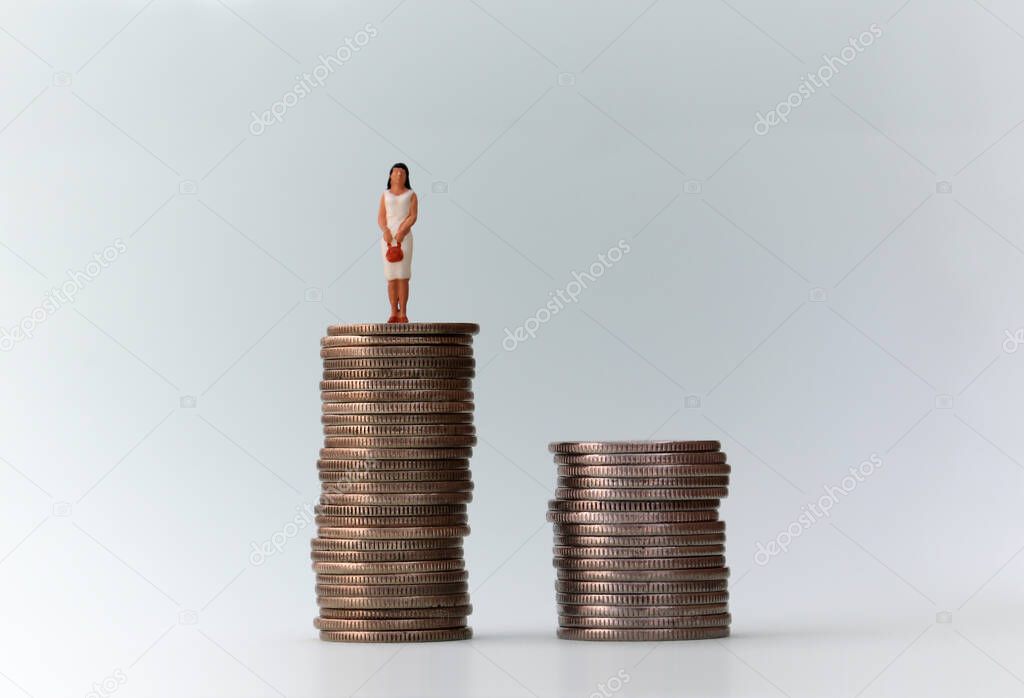 A piles of coins and a miniature people standing on a pile of coins.